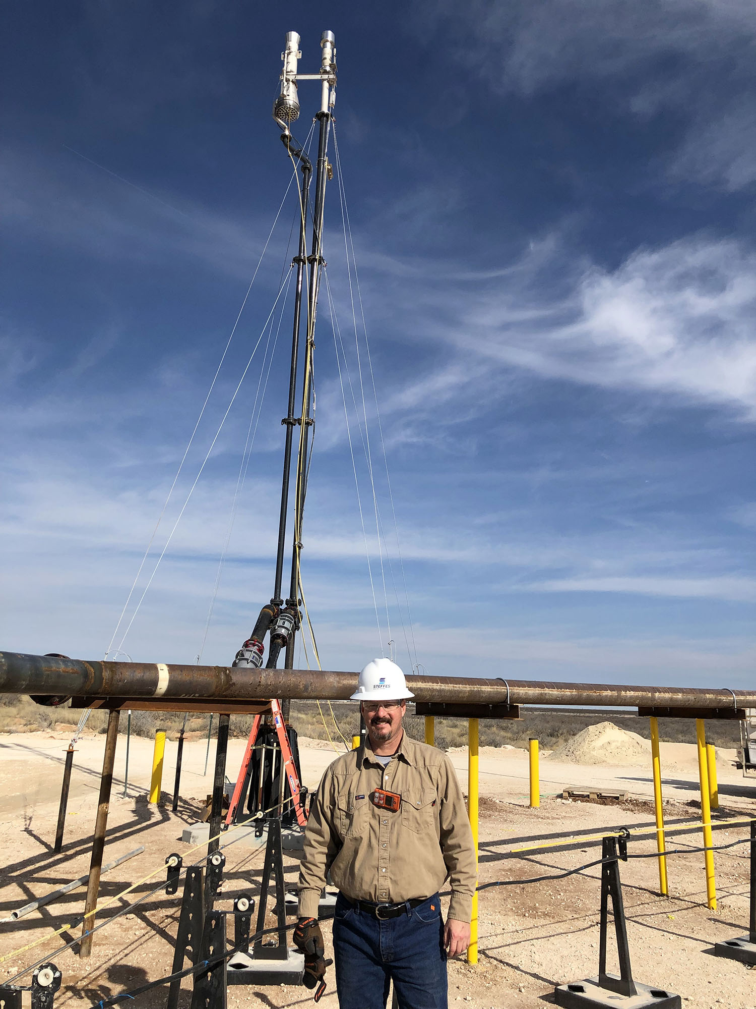A photo of Joe Pisklak, a Steffes Key Account Manager for the Permian, in front of a Steffes flare on an oil and gas well site in the Permian Basin